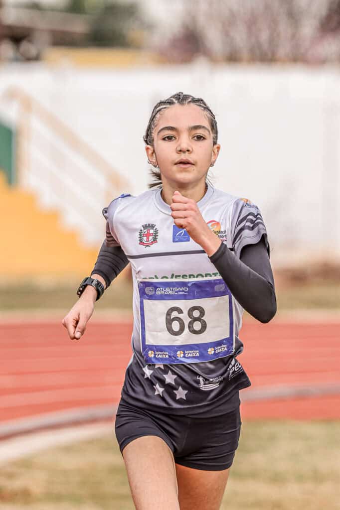 Atleta jovem correndo em pista de corrida, promovendo saúde e esporte.