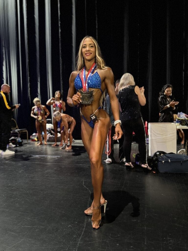 1. Mulher atleta de fitness com medalha, usando biquíni de competição azul brilhante.