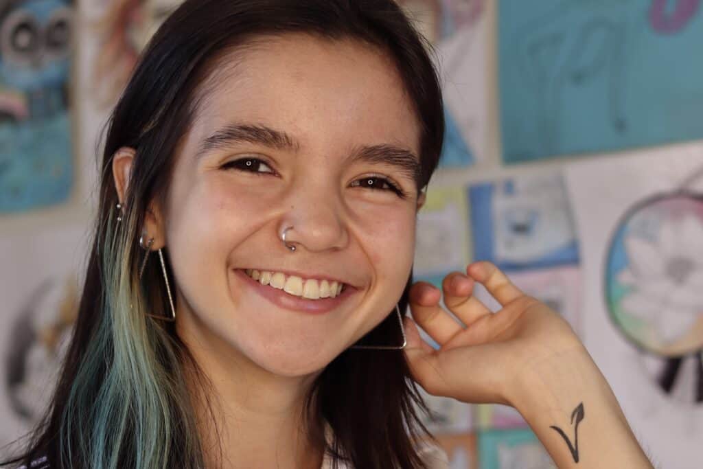 Sorriso de jovem com cabelo colorido e acessórios, promovendo a marca UAI Tofu.