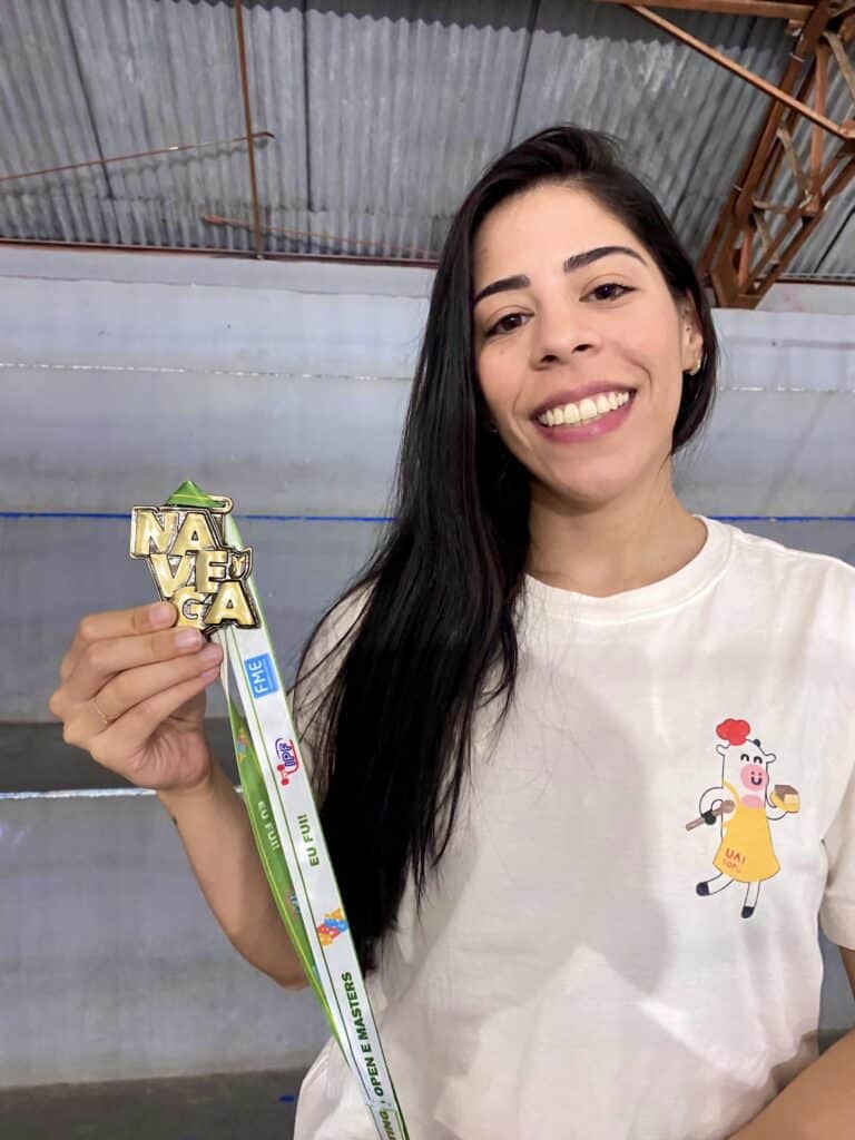 1. Medalha UAI Tofu, prêmio de destaque em culinária vegetariana, com mulher sorridente segurando a medalha.