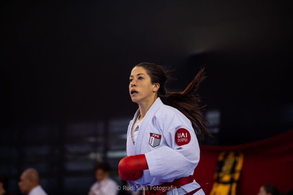 Judoca feminina em ação usando kimono com logos UAI Tofu e FPK, foco em esporte e artes marciais.
