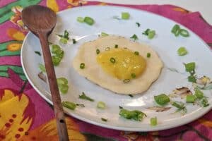 Ovo de tofu com gema de abacate, decorado com cebolinha, servido em prato floral.